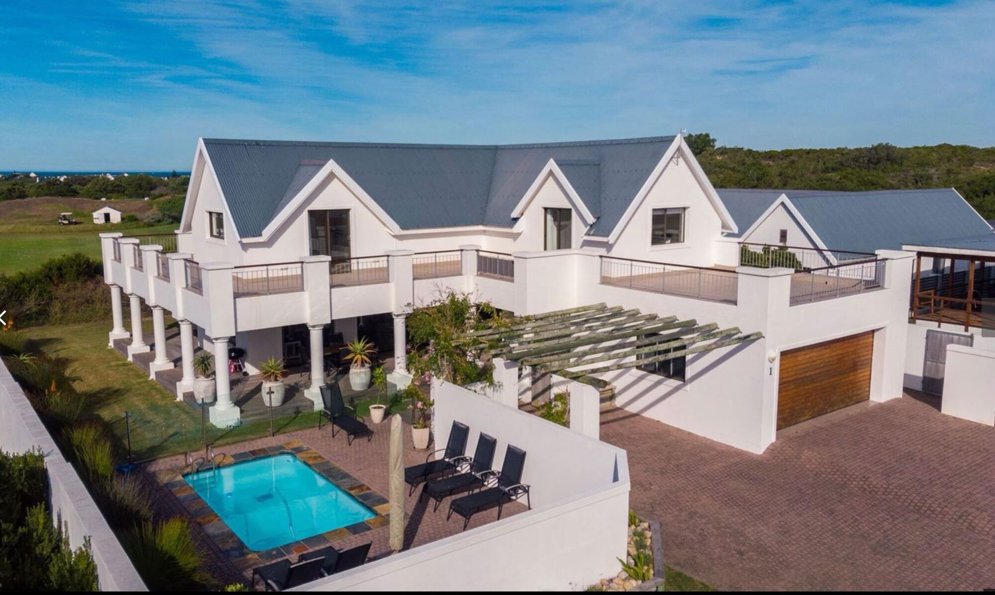 Aerial view of Wildehaven with its pool and courtyard, the St Francis Links driving range and the sea beyond