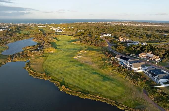Aerial view of a lakeside hole with the ocean behind